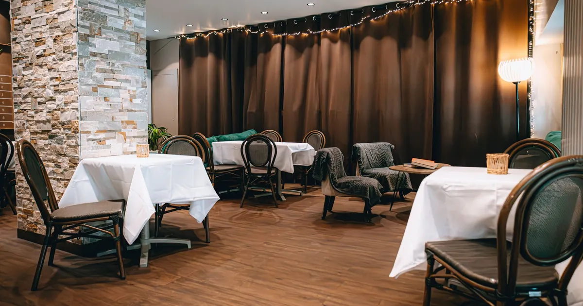 Tables with white cloths and bentwood chairs in a small restaurant dining room